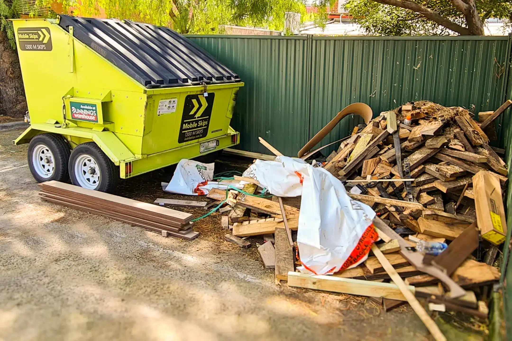 Image of mobile skips standard skip bin hire parked outside next to pile of rubbish to be removed - Skip bin hire Australia